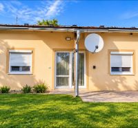 A family house in Martovce with white windows, a satellite dish, and a manicured lawn.