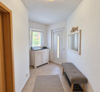 Bright entrance hall in a family house with a bench and a mirror on the wall.
