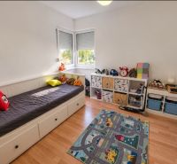 Children's room in a family house with a bed and storage space, floor with wooden decor.