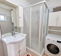 A bathroom in a family house with a sink, shower, and washing machine.