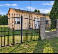 A family house in Martovce with a grassy plot and a metal fence.
