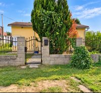A family house in Martovce with a front garden and a metal gate, surrounded by a hedge.