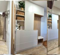Cozy bathroom with wood-patterned flooring, a shower, a washing machine, and storage space.