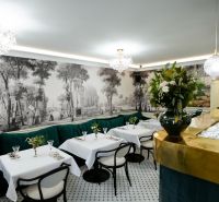 Interior of commercial spaces with white tables, green sofas, and wall paintings.