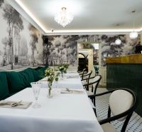 Interior with historical wallpaper, tables, green sofas, and a crystal chandelier in commercial premises.