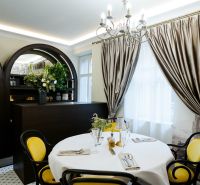 Dining table with a white tablecloth and yellow chairs in a commercial space.