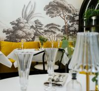 Interior of commercial spaces with white tables, yellow chairs, and a wall mural of a forest.