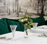 An elegantly set table with a white tablecloth, a vase with flowers, and crystal glasses.