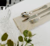 A table set with cutlery and a glass, decorated with flowers on the table.
