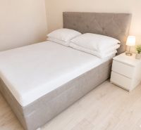 A bed with a nightstand and a lamp in a 2-room apartment on a floor with a wooden decor.
