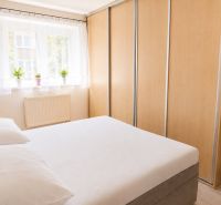 Bedroom in a 2-room apartment with a bed, wardrobes, and a window with plants.