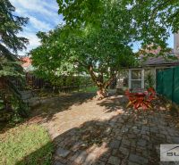 In the garden of a family house on Hlavná Street in Štefanová, there is seating under a leafy tree.