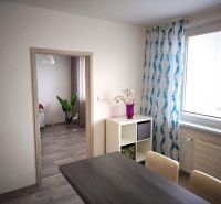 Interior of a 1-room apartment with a wooden decor floor, colorful curtains, and decorations.
