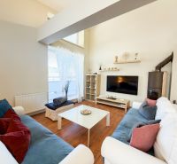 Living room in a three-room apartment with a wooden decor floor, comfortable couches, television.