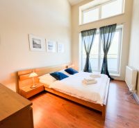 A bedroom in a 3-room apartment with a wooden decor floor and large windows.