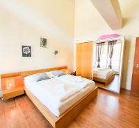 Bedroom with a bed and a large wardrobe, set on a floor with a wooden decor.