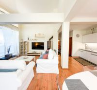 Living room with wood-patterned flooring in a 3-room apartment, light furnishings, kitchenette.