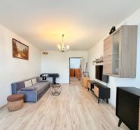 Living room in a 3-room apartment with a wood-patterned floor, gray sofa, and foosball table.