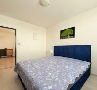 A bedroom with a gray floor in a 3-room apartment, simple furniture, and a painting on the wall.