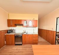 A kitchen in a 3-room apartment with a wooden decor floor and a kitchen unit.