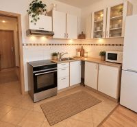 A kitchen with white cabinets and appliances in a two-room apartment.