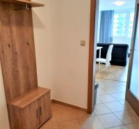 The entrance hall in a 2-room apartment with a coat rack and a view into the living room with a dining area.