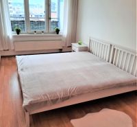 A bright bedroom in a two-room apartment with a window and a wooden decor floor.