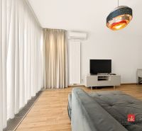 Living room in a two-room apartment with a sofa, TV, and curtains on a floor with wooden decor.