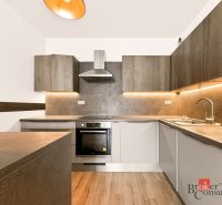 A kitchen in a 2-room apartment with a wooden decor floor and illuminated cabinets.
