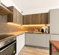 A kitchen with a corner unit, equipped with appliances, and a floor with a wood decor.