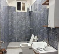 Bathroom in a 2-room apartment with ceramic tiles and white sanitary equipment.
