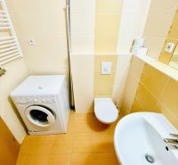 Bathroom in a studio apartment with a washing machine, sink, and toilet.