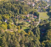 Aerial view of green recreational plots in Štiavnické Bane with house roofs.