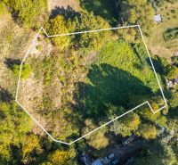 Aerial view of recreational plots in Štiavnické Bane surrounded by greenery and neighboring gardens.