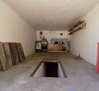 Garages with a maintenance pit and storage spaces with shelves and wooden surfaces.
