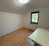 A room with a wooden decor floor, a table, and a window in a family house.