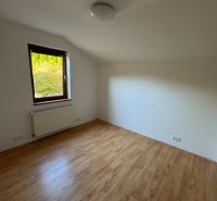 A room in a family house with a wooden decor floor and a radiator under the window.