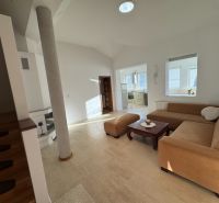 Living room in a family house with a beige sofa and access to the kitchen.