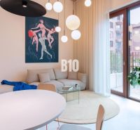 Living area with white furniture, a round table, and art in a 2-room apartment.