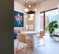 Dining area in a 2-room apartment with an art painting and pendant lights.