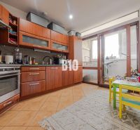 A kitchen in a 3-room apartment with a wooden decor floor and a balcony.
