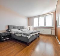 A bedroom with a large bed, a nightstand, and a wooden decor floor in a 3-room apartment.