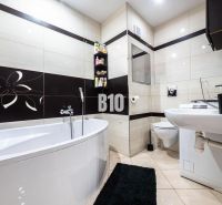 Bathroom in a 3-room apartment with a bathtub, toilet, and black-and-white decor.