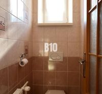 A small bathroom with a window, tiles, and a toilet in a family house.