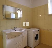 A bathroom in a family house with a washing machine and yellow tiles.