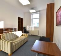Office with a striped sofa, desk, and shelf, simple interior.