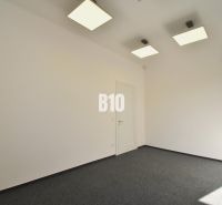 Empty office with white walls, gray carpet, and geometric lights on the ceiling.