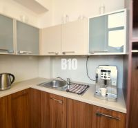 A kitchenette with a coffee maker and an electric kettle in an office with wooden decor.