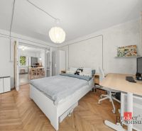 A bedroom with wood-patterned flooring and a desk in a two-room apartment.