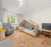Children's room with a wooden decor floor, a house-shaped bed, and an armchair.